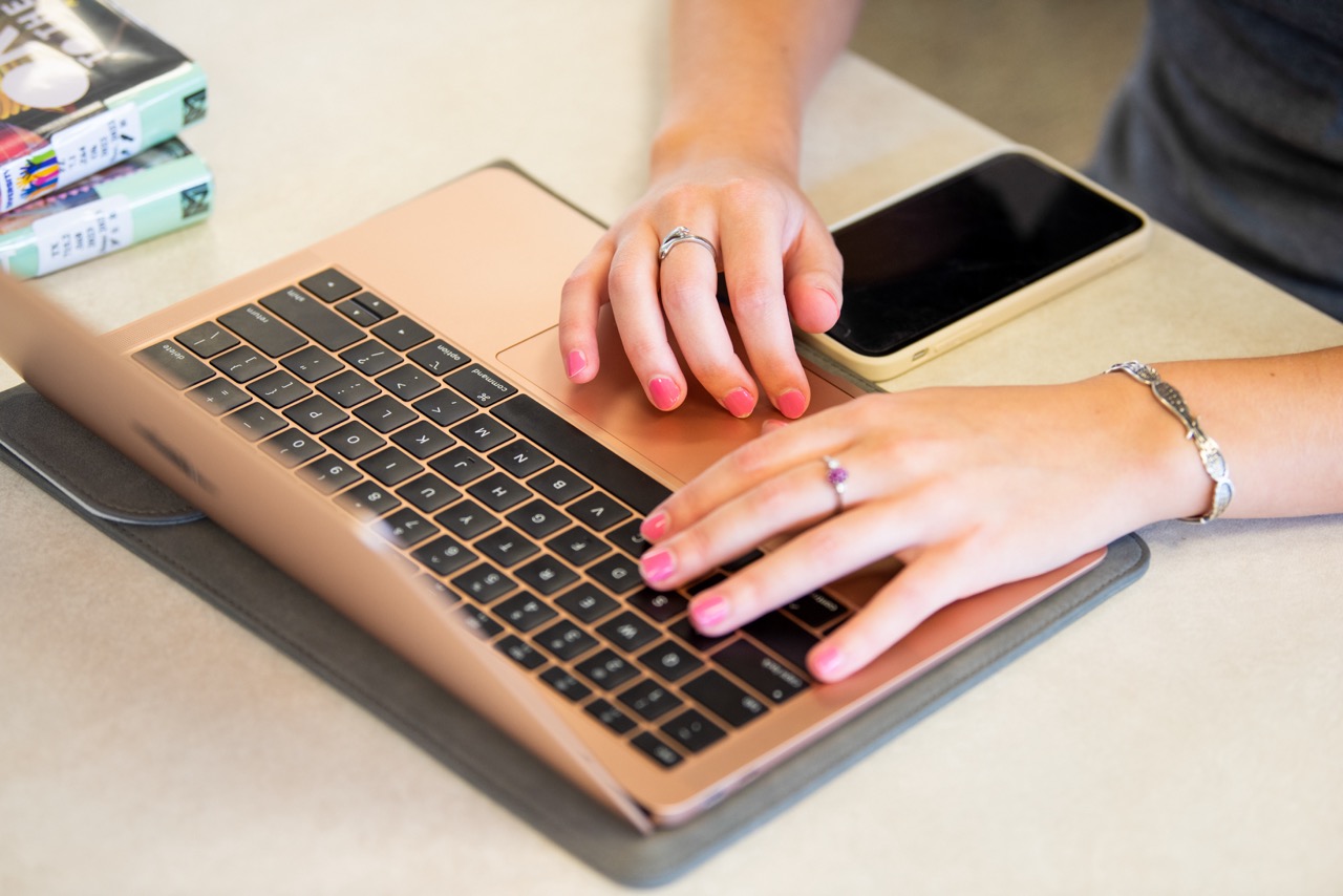 A woman's hands typing on a laptop
