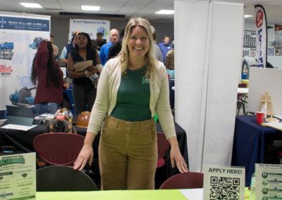 A woman wearing a Sustainable Plumbing shirt smiles.