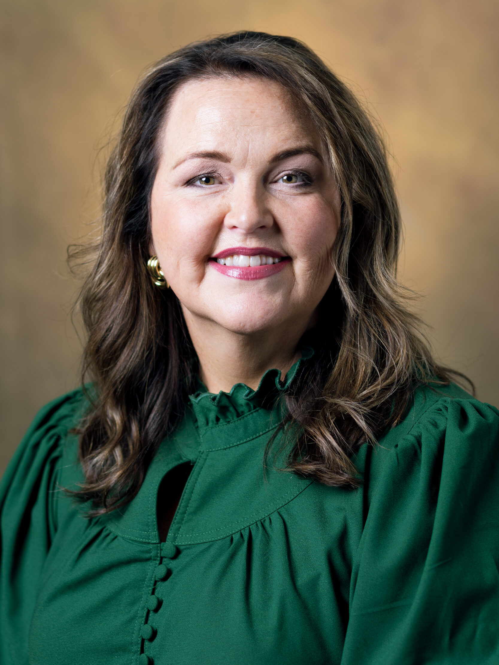 Vanessa Miles is a green Blouse smiling, her hair is in loose curls over her shoulders